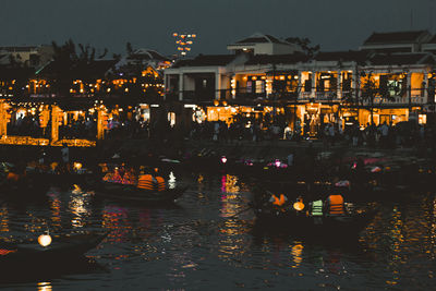 Illuminated buildings by river in city at night