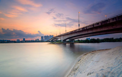 Bridge over river against cloudy sky