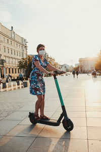 Young woman riding an electric scooter in the city center. woman wearing the face mask