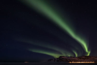 Scenic view of aurora borealis over snow covered landscape against star field at night