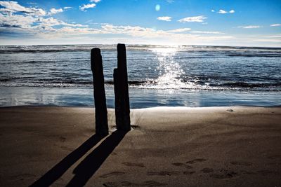 Wooden posts on beach against sky