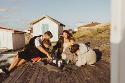 Family with children sitting on blanket outside cabin during summer