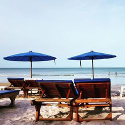 Chairs and tables on beach against sky