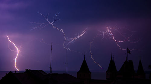 Lightning over buildings against sky at night