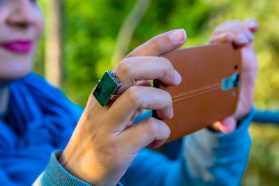 Cropped image of woman photographing by mobile phone in forest