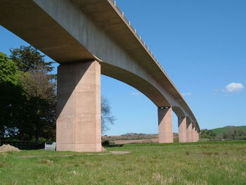 Low angle view of arch bridge on field against sky