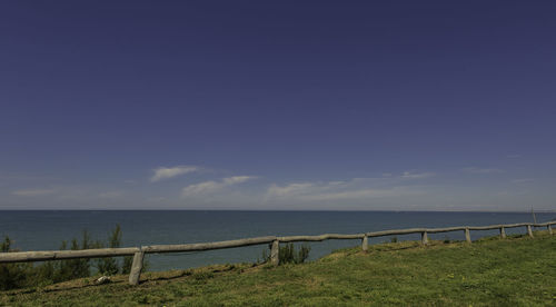 Beach with grass, wooden fence and morning light. calm blue sea. clear sky, sunny day. chipiona