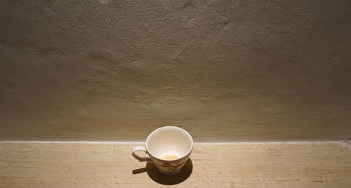 High angle view of coffee cup on table against wall