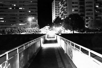 Illuminated street amidst buildings in city at night