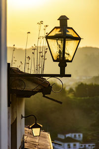 Illuminated street light against sky at sunset