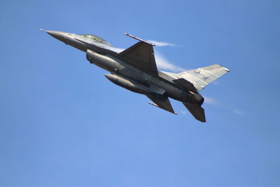 Low angle view of airplane flying against clear blue sky