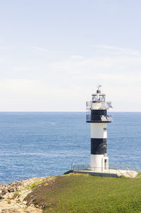 Lighthouse by sea against sky