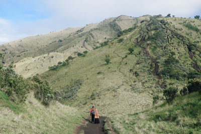 Rear view of women walking on mountain against sky