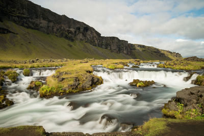 Scenic view of sea by mountains against sky