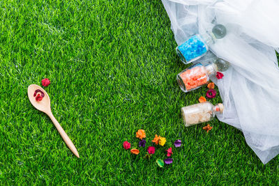 High angle view of rock salt in jar with flowers on grass