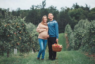 Full length portrait of smiling man standing in basket on field