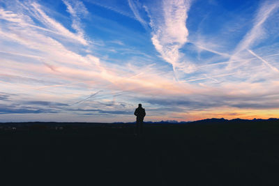 Silhouette man standing on land against sky during sunset