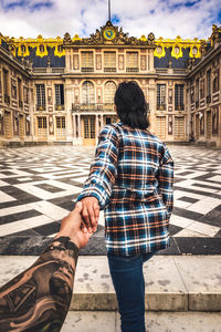 Rear view of man and woman standing on street against building