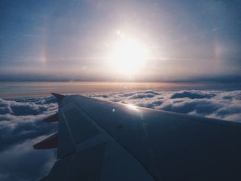 Aerial view of airplane wing over sea against sky during sunset