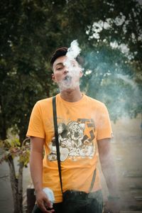 Young man wearing sunglasses standing against trees