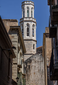 The medieval tower of sant peter's church among historical mediterranean houses in figueres, spain.