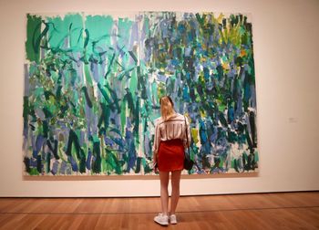 Rear view of woman standing against wall in museum