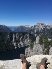 Low section of woman on mountain against clear sky