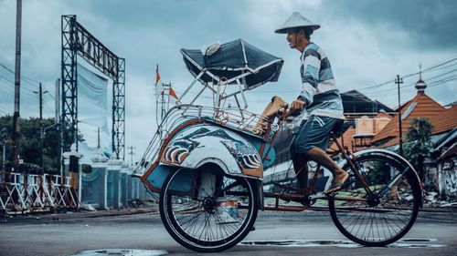 Man riding pedicab on road in city