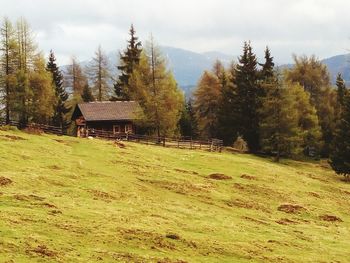 View of house on landscape against cloudy sky