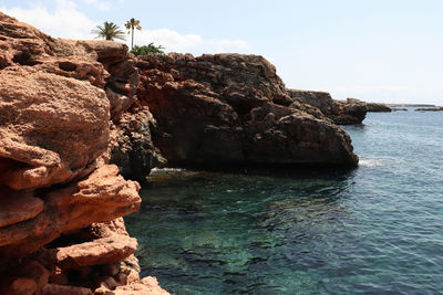 Rock formation in sea against clear sky