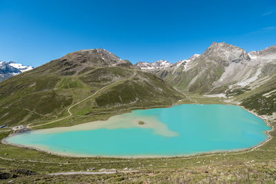 Scenic view of lake and mountains against blue sky