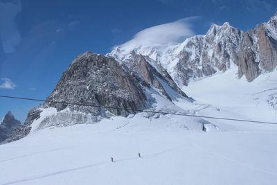 View of people skiing on snowcapped mountain against sky