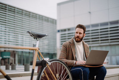 Portrait of man using mobile phone while sitting on chair