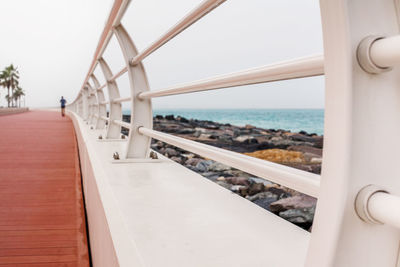 A man runs along a beautiful promenade with a white fence.