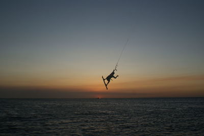 Silhouette bird flying over sea against clear sky