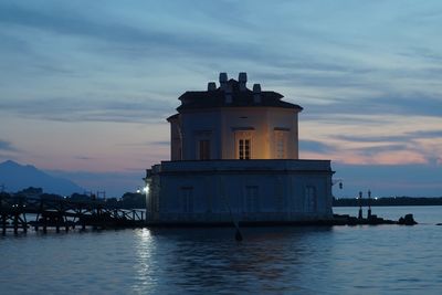 View of lighthouse by sea against sky during sunset