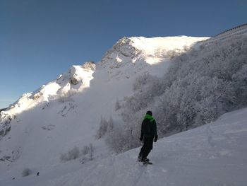 Rear view of man on snowcapped mountain against sky