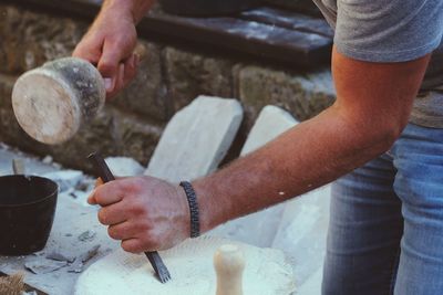 Midsection of man shaping rock