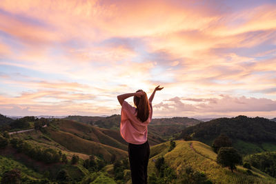 Woman standing on mountain against sky during sunset