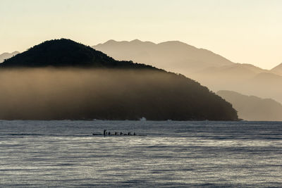 Scenic view of sea and silhouette mountains against sky