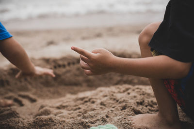 Midsection of hands on sand at beach