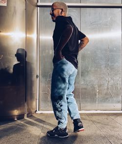 Side view of young man standing against wall