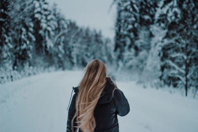 Rear view of woman standing on snow covered landscape