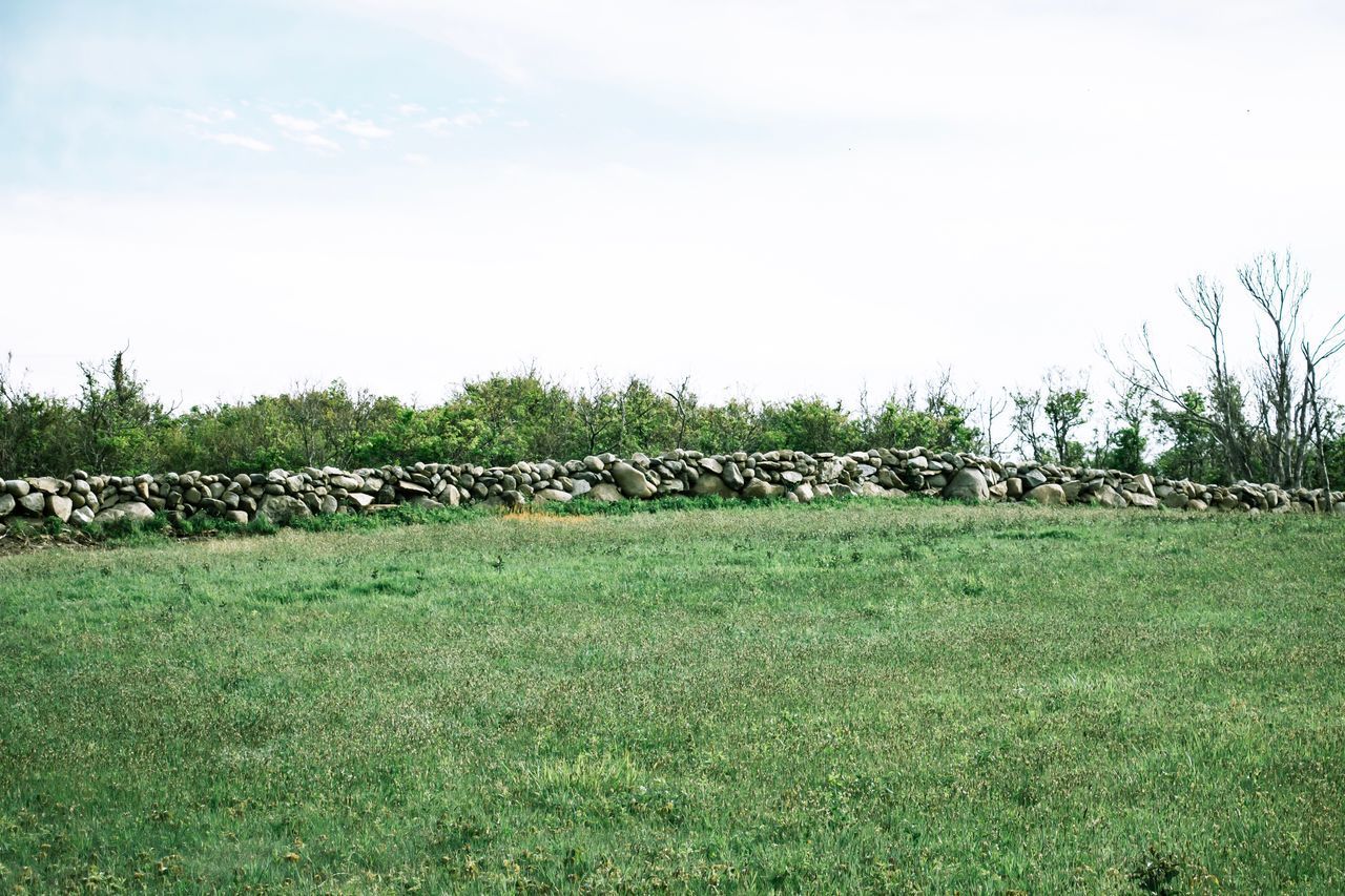 STACK OF STONES ON FIELD AGAINST SKY