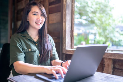 Young woman using phone while sitting at table