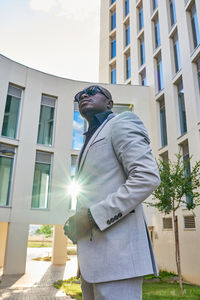 African-american businessman between buildings, with the sun on his back person