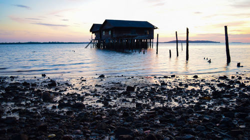 Lifeguard hut on pier at beach during sunset