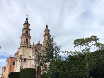 Low angle view of trees and building against sky