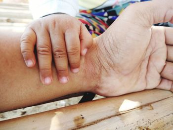 Midsection of daughter holding cropped father hand