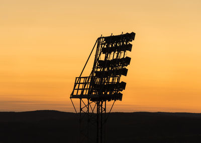 Low angle view of silhouette cranes against sky during sunset